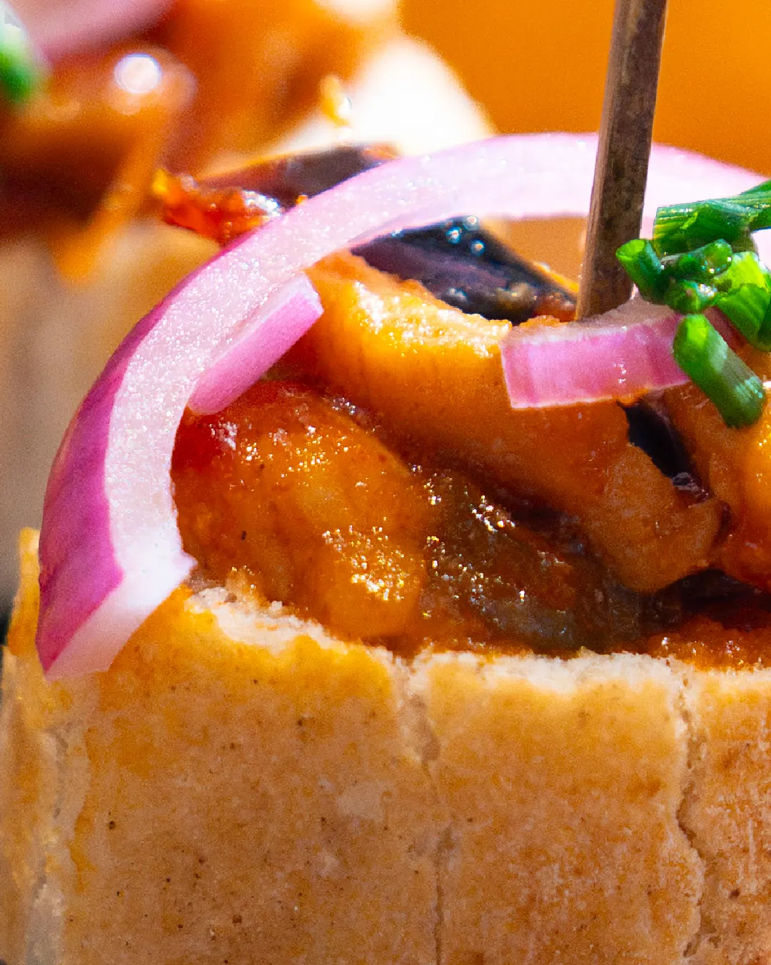 Gros plan d'un pincho : pain, garniture mijotée, oignon rouge et ciboulette