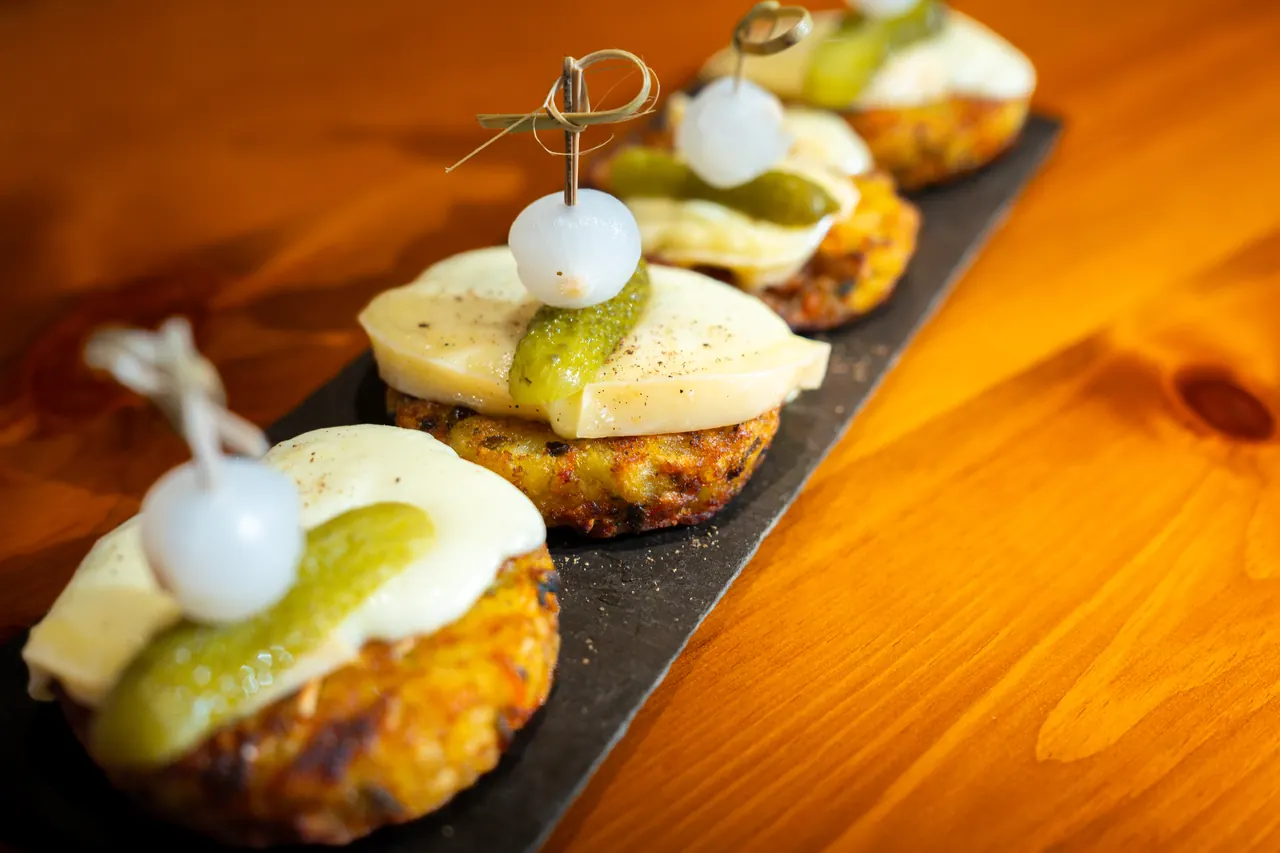 Pinchos à la raclette, cornichon et oignon grelot sur une ardoise